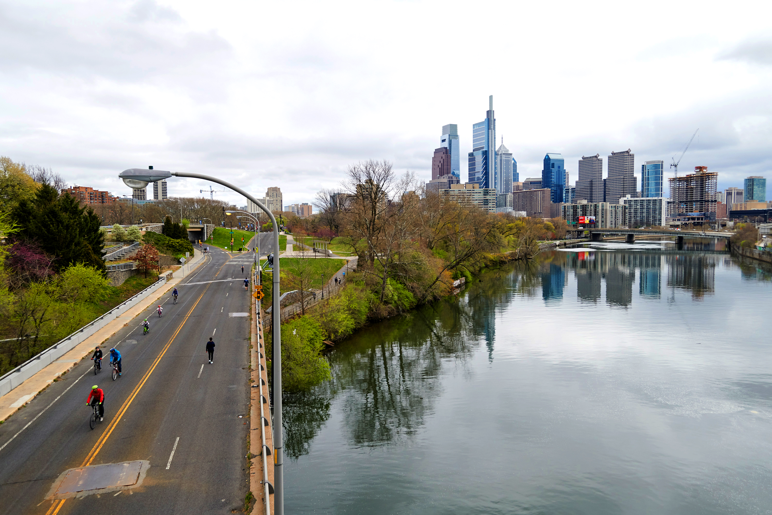 Cyclists on MLK drive with the Schuylkill River alongside and Philadelphia skyline in the background
