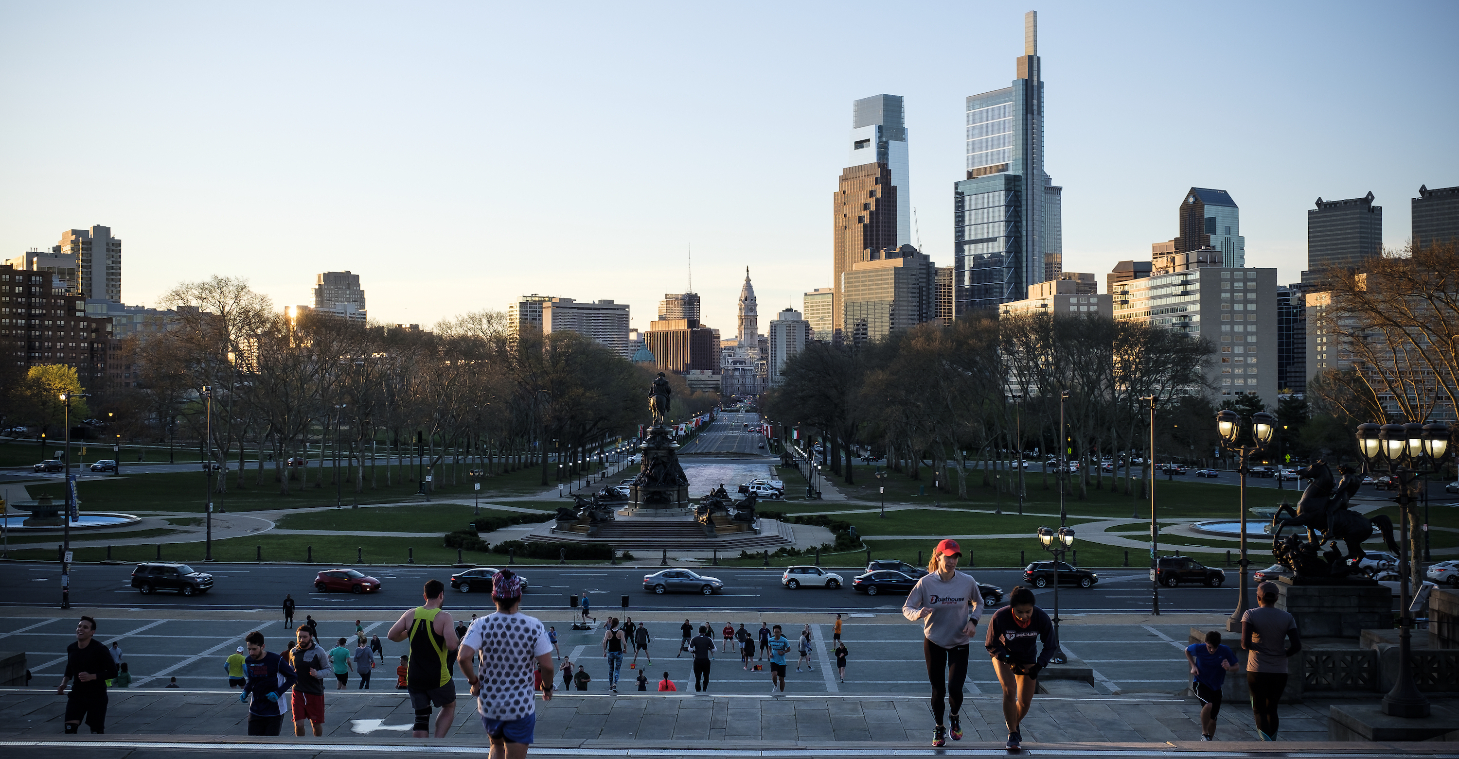 View of people running up the steps at the Philadelphia Museum of Art with the skyline in the background.