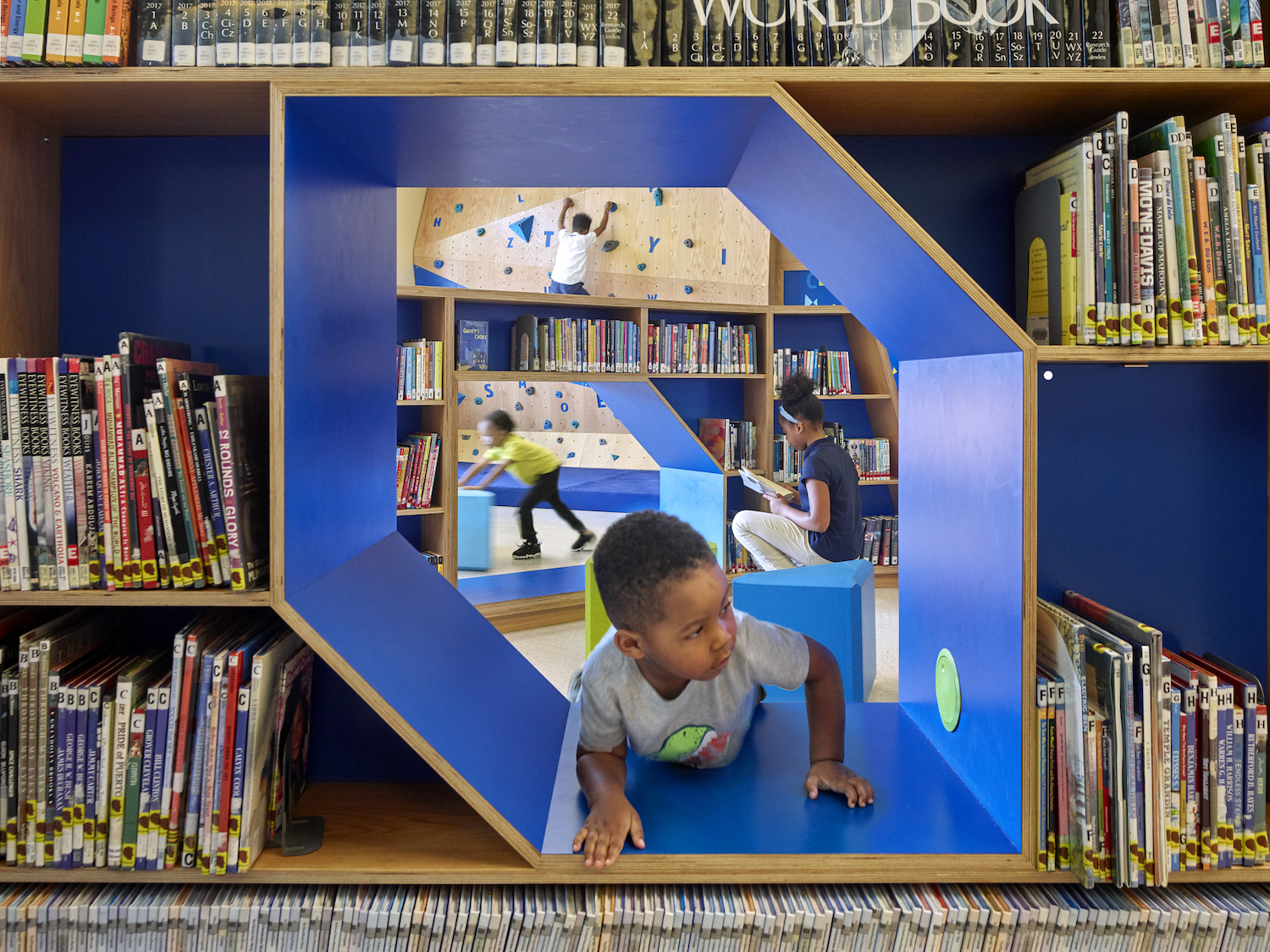 Child crawls through a play area built into bookshelves at branch of the Free Library of Philadelphia