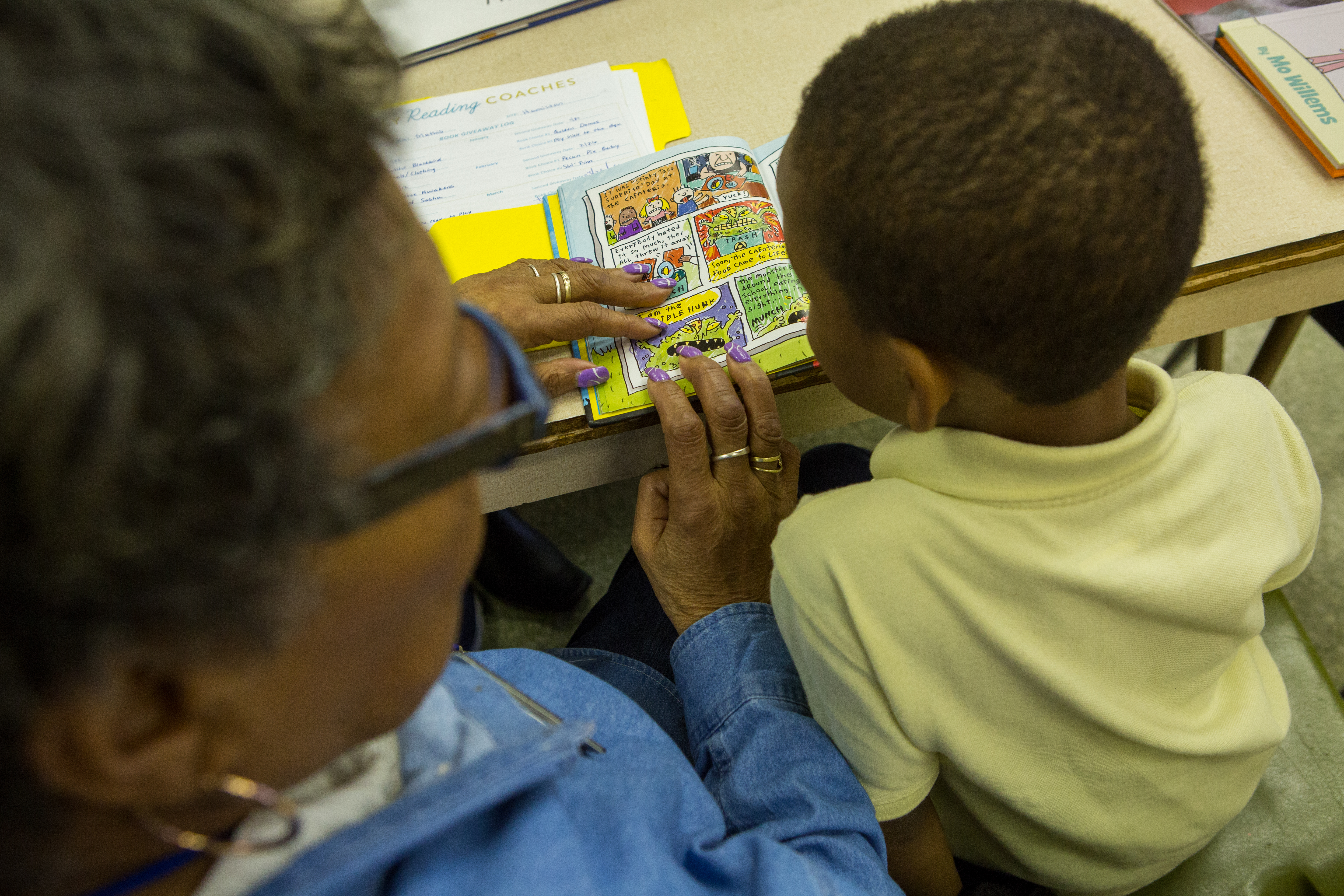Teacher and young child reading a comic book