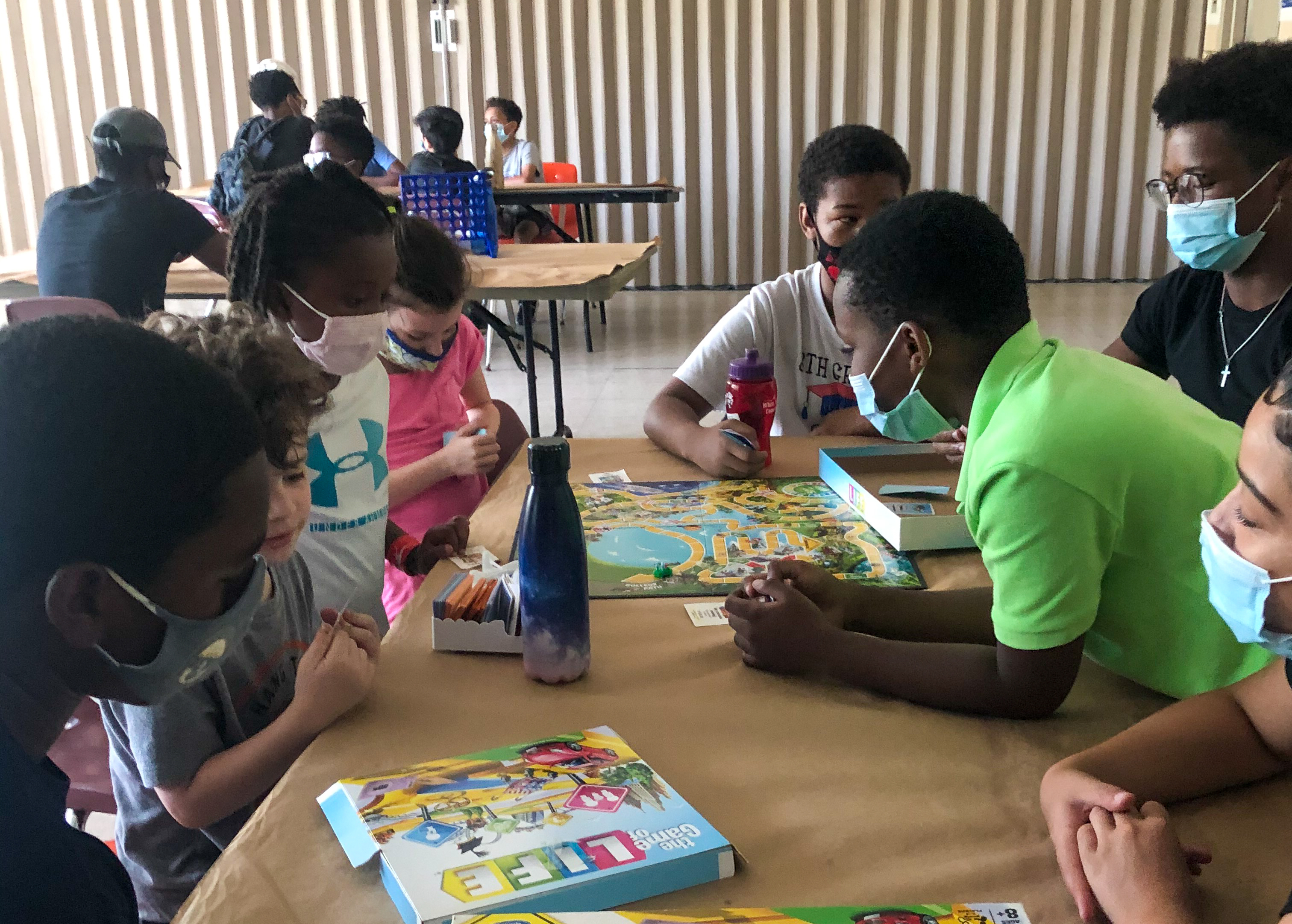 A group of children gathered around a table playing LIFE