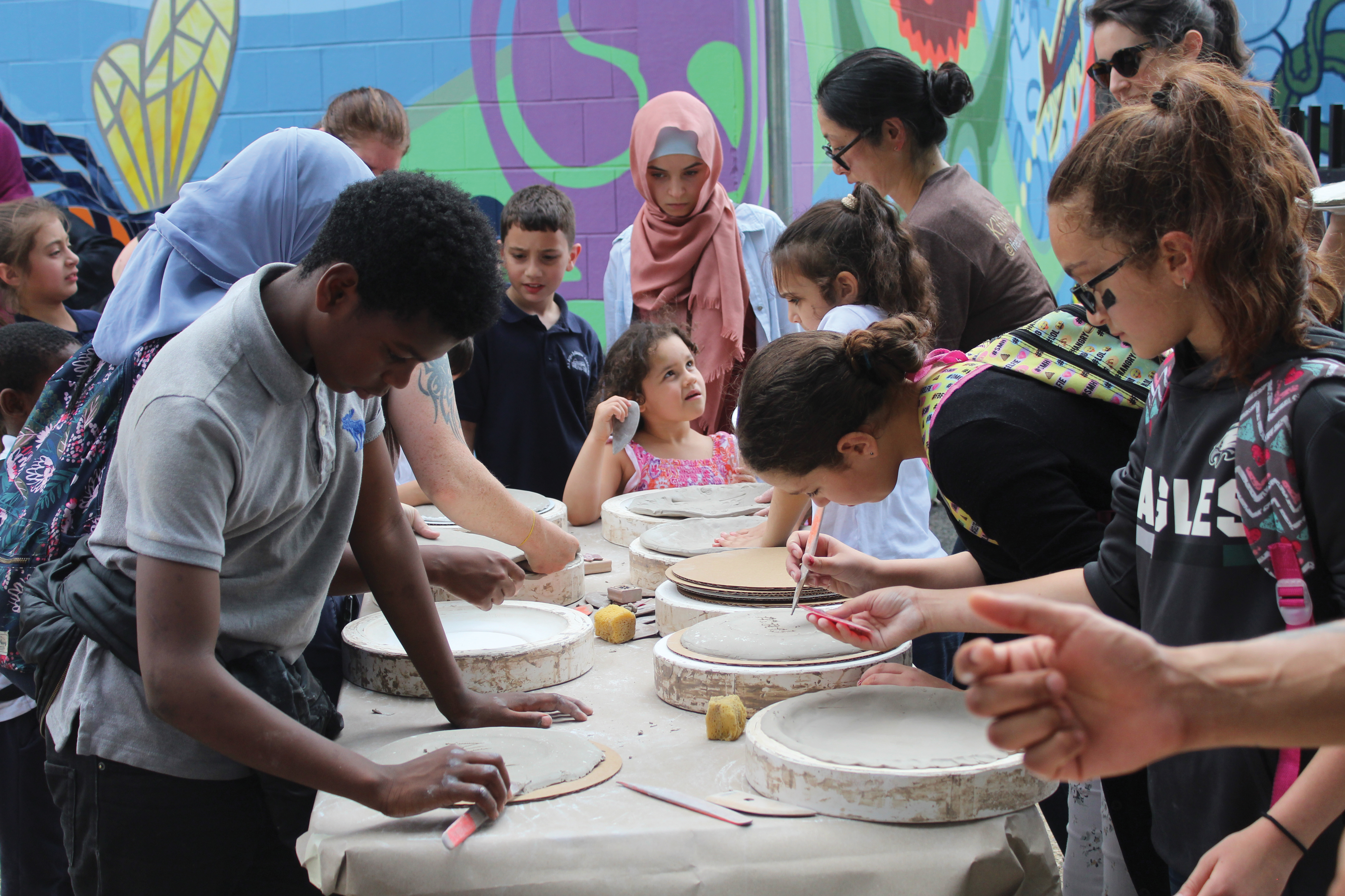 A group of students gathered around a table, working with clay.