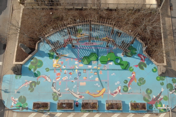 An overhead view of a mural of koi fish in a pond, painted on a plaza. 